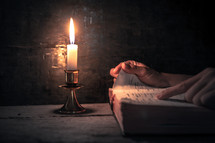 a man reading a Bible by candlelight 