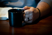 man reading a Bible and drinking coffee