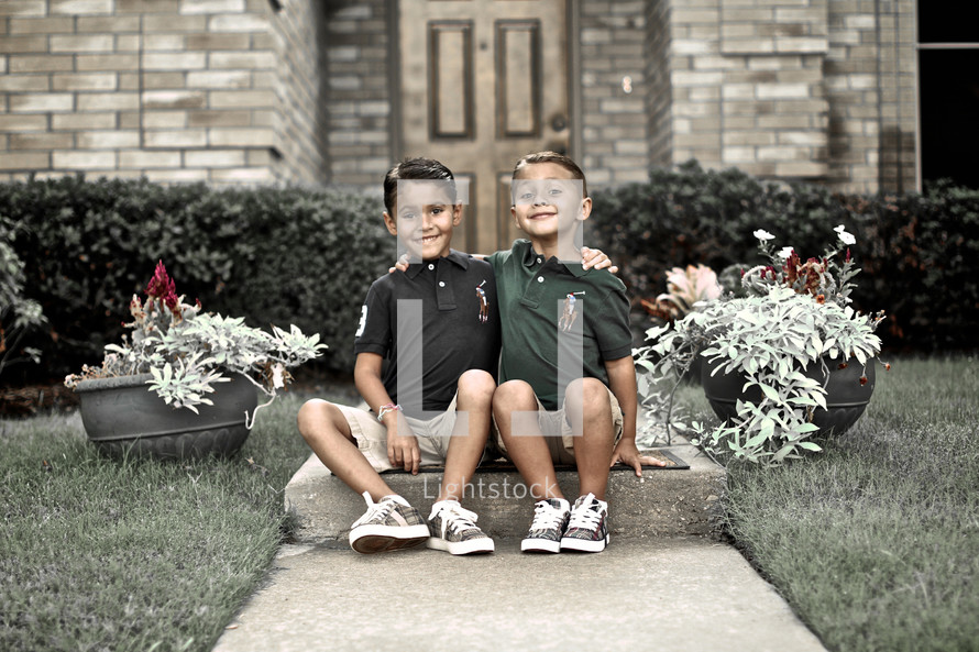 brothers sitting on a sidewalk together