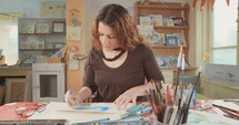 Female artist painting in her studio with water colors and pencils