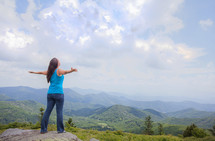 woman standing standing on a rock with outstretched arms 