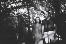 couple holding hands standing in a forest 