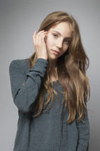 a teen girl tucking her hair behind her ear 