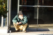 a homeless man sitting on a curb 