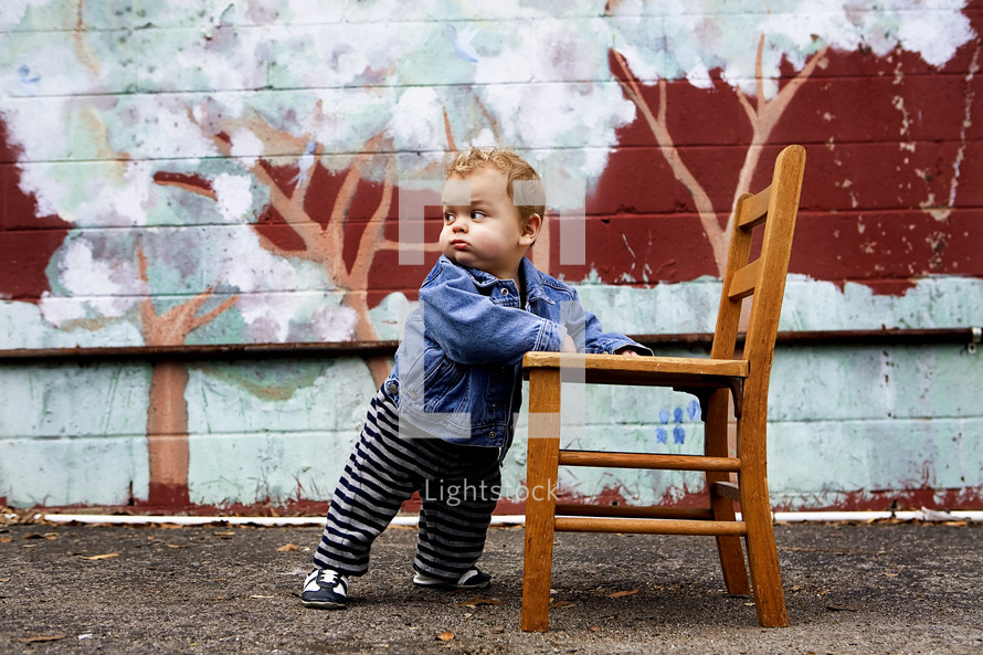 toddler boy holding onto a chair to stand