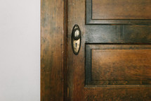 A wood panel door with a bronze door knob.