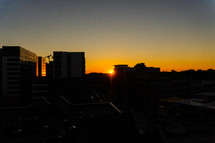 sun setting behind city buildings 