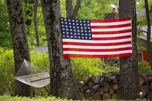 hammock, firewood, and American flag between trees