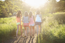 girls walking down a dirt path towards glowing sunlight, seeking the holy spirit 