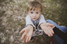 a child reaching up with empty hands 