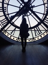 a woman standing in front of a clock in a clock tower 