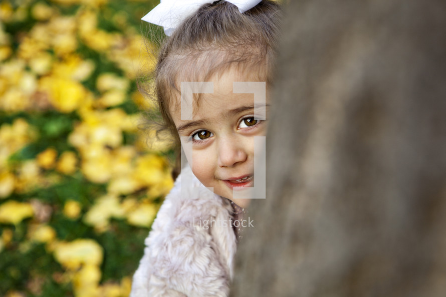 girl peeking around a tree