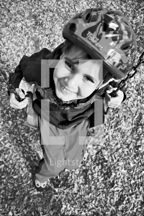 child on a swing wearing a bike helmet