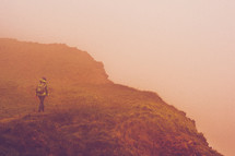 person hiking a dusty foggy landscape 