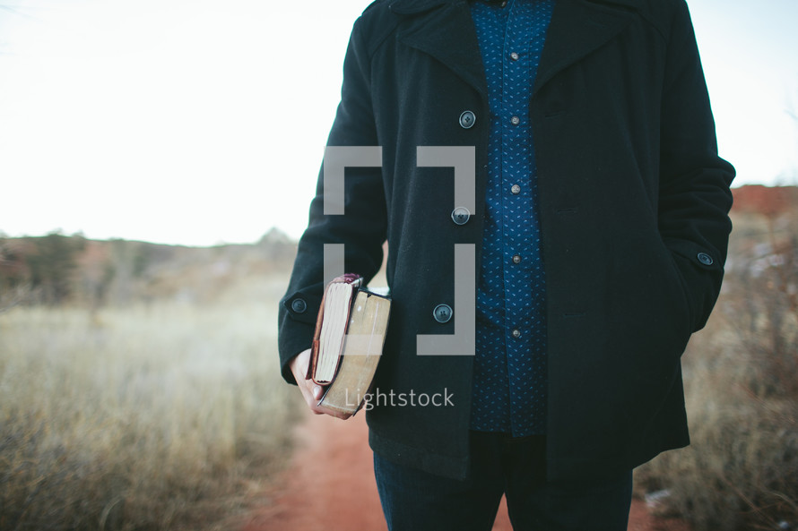 man holding a Bible and journal at his side 