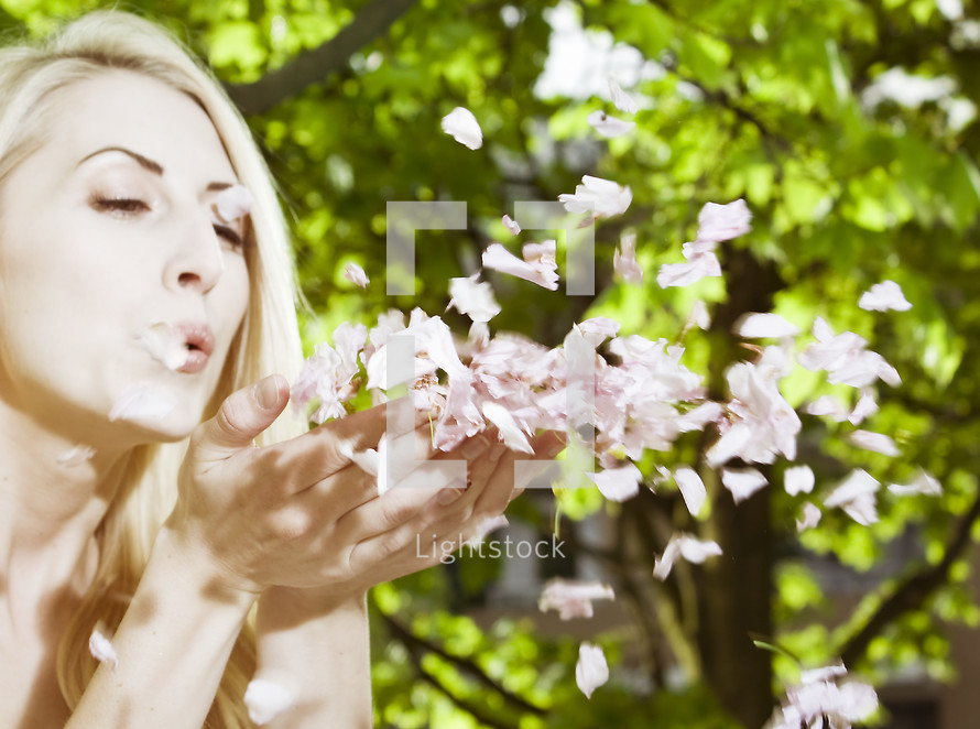 woman blowing petals; floating petals