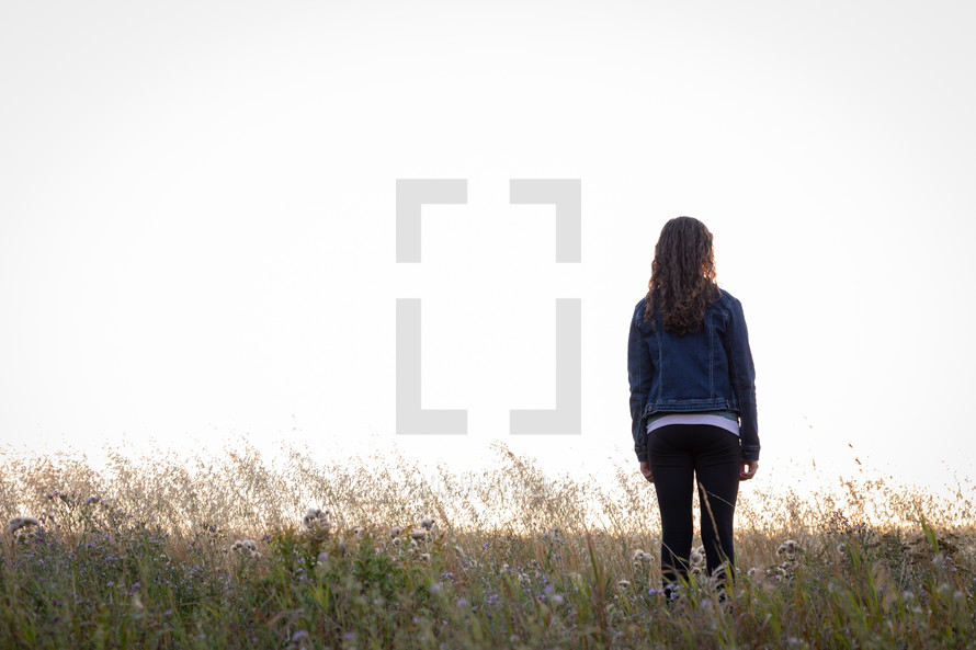 a teen girl standing in a field 