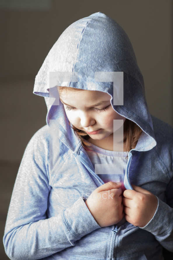A little girl wearing a lavender hooded sweatshirt.