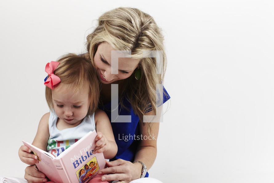 mother reading a children's bible to her toddler daughter