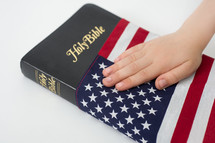 Hand on a Holy Bible wrapped in an American flag.