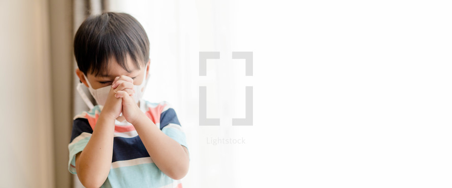 a child praying wearing a face mask 