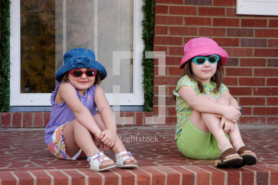 girls in sunglasses sitting on a front porch 