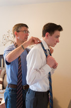 a father helping his son put on a tie 