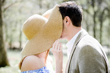 a man and woman kissing under a sunhat 