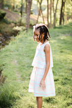 An African American girl standing outdoors in the grass 