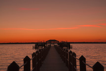view down a long pier at sunset 