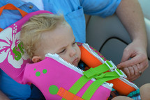 a toddler boy n a life vest on a boat 