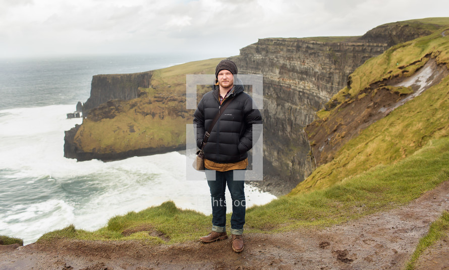 man standing at the edge of cliffs along a shoreline in Scotland