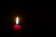 flame on a red candle in darkness 