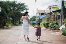a mother walking holding hands with her daughter outdoors 