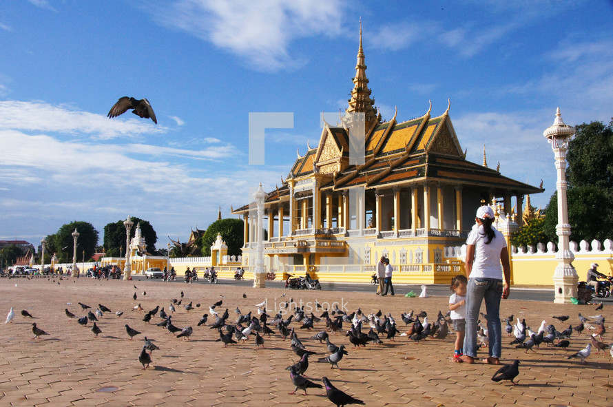 Mother and daughter feeding birds outside the Royal Palace in Cambodia