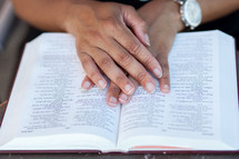 hands on the pages of a Bible 