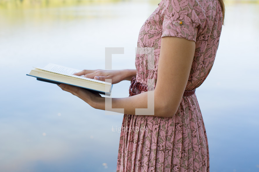 a woman in a pink dress reading a Bible 