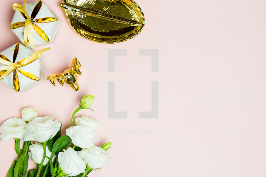 white flowers, gold dish, and gifts on a pink background 