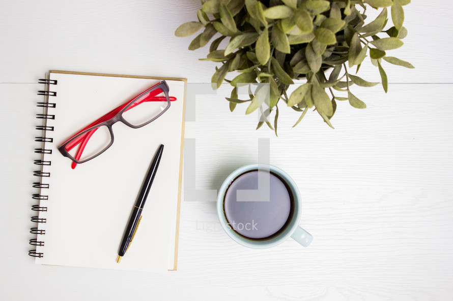 reading glasses, notepad, and coffee cup 