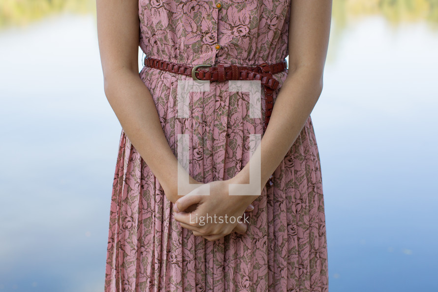 torso of a woman in a pink dress clasping her hands together 