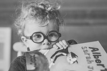 a child with glasses holding a book 