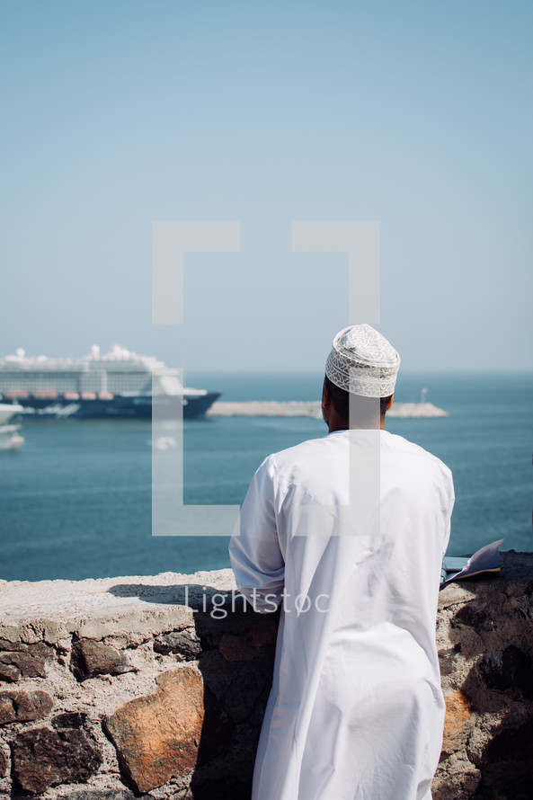Omani man looking at the scenic view from the Muttrah Fort in Muscat, Oman