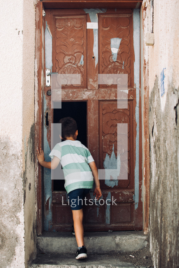 Little boy looking in an old door in Muttrah, Muscat, Oman