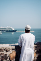 Omani man looking at the scenic view from the Muttrah Fort in Muscat, Oman