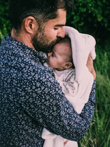 father holding a newborn outdoors 