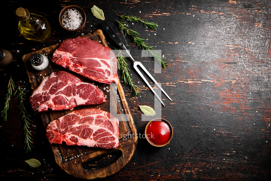 Raw pork steak on a stone board. On a black background. High quality photo