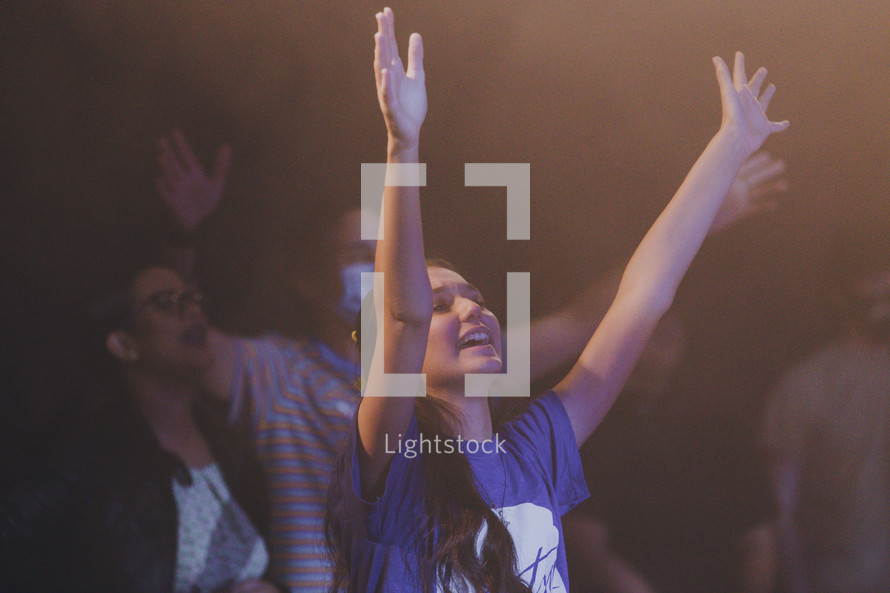 teen girl with hands raised during a worship service 