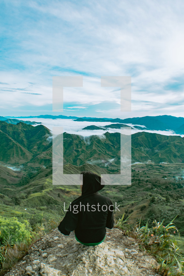 person looking out at green mountaintops 