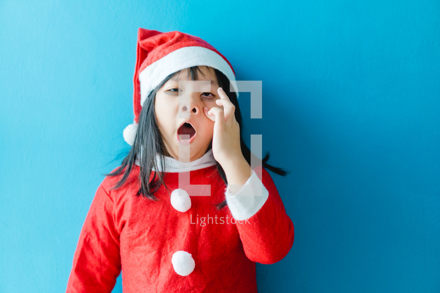 a sleepy little girl in a Santa Claus suit 