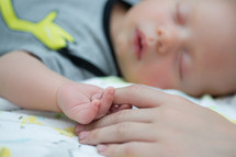 infant son holding mom's finger 